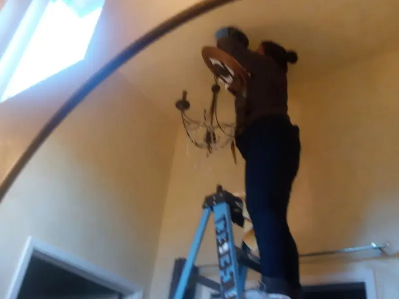 Electrician installing a chandelier in a Cypress Gardens residence